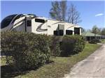 A fifth wheel trailer parked behind some shrubs at CAMPGROUNDS OF THE SOUTH - thumbnail