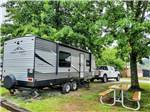A travel trailer hitched to a white truck in a RV site at WESTGATE RV CAMPGROUND - thumbnail
