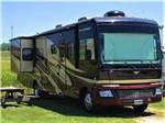 Class A motorhome parked next to a picnic bench at WESTGATE RV CAMPGROUND - thumbnail