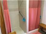 View larger image of The shower stalls with salmon color curtains at CLOUD NINE RV PARK image #5