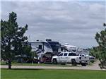 View larger image of Grassy area with trees and 5th wheels in the distance at A PRAIRIE BREEZE RV PARK image #11