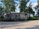 A fifth wheel parked next to a picnic bench at ARROWHEAD RV PARK - thumbnail