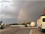 Rainbow arches over desert RV campground with mountains in background at DE ANZA RV RESORT - thumbnail