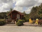 A rental cabin with Adirondack seating in front at ASHLAND/HUNTINGTON WEST KOA HOLIDAY - thumbnail