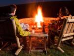 A couple sitting near a fire ring in the evening at ASHLAND/HUNTINGTON WEST KOA HOLIDAY - thumbnail