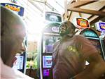 View larger image of A couple of men laughing in front of slot machines at LITTLE RIVER CASINO RESORT RV PARK image #5