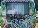Woman peering out the window of her RV at a blue bicycle at CEDAR VALLEY RV PARK - thumbnail