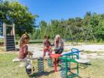 A mom with her kids at the playground at SWAN CREEK COMMUNITY (MHP) - thumbnail