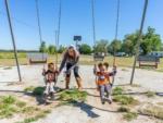 Two kids on the swings being pushed by their mom at SWAN CREEK COMMUNITY (MHP) - thumbnail