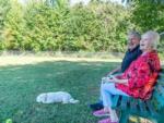 A couple with their dog in the fenced pet area at SWAN CREEK COMMUNITY (MHP) - thumbnail