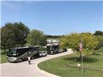 View larger image of Two large RVs parked in a row on gravel road at PECAN PARK RIVERSIDE RV PARK image #7