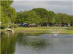 Boat docked at pond with fountain in the middle at BLUEBONNET RIDGE RV PARK & COTTAGES - thumbnail