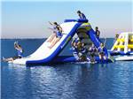 Kids playing on the inflatables in the water at EMERALD LAKE TRAILER RESORT & WATERPARK - thumbnail