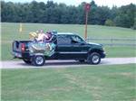 A truck with people in the back dressed in Mardi Gras decor at ADIRONDACK GATEWAY CAMPGROUND - thumbnail