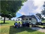 A family eating outside of their trailer at WHITE ACRES CAMPGROUND - thumbnail
