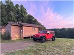 A Jeep parked by a rental cabin at dusk - thumbnail