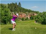 A female golfer taking a tee shot at Elkhorn Ridge RV Resort & Cabins - thumbnail