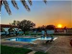 View larger image of The swimming pool at dusk at LAZY PALMS RANCH RV PARK image #1