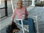 View larger image of Woman in white rocking chair petting black dog at EZ DAZE RV PARK image #11