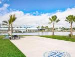 RV lot by grassy area with palm trees, picnic bench and water at CAMP MARGARITAVILLE RV RESORT BREAUX BRIDGE - thumbnail