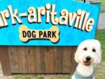 Dog sitting in front of a Bark-aritaville dog park sign at CAMP MARGARITAVILLE RV RESORT BREAUX BRIDGE - thumbnail