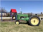 View larger image of A John Deere tractor in front of the playground equipment at CROSSROADS RV PARK image #2
