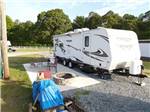 A travel trailer parked in a gravel site at FOUR OAKS LODGING & RV RESORT - thumbnail