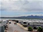 A row of RVs parked in sites with mountains in the background at CAMPBELL COVE RV RESORT - thumbnail