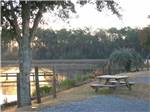 View larger image of A picnic table by the water at sunset at AVALON LANDING RV PARK image #12