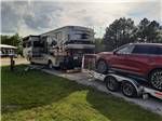 A motorhome pulling a trailer parked in a paved site at PARKERS CROSSROADS CAMPGROUND - thumbnail