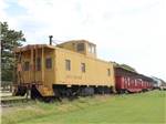 A yellow caboose at the end of a long train at COVERED WAGON RV RESORT - thumbnail