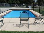 A pool with black wrought-iron chairs at COVERED WAGON RV RESORT - thumbnail