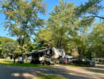 Camper by trees at Rustic Acres RV Resort & Campground - thumbnail