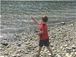 A boy throwing a rock into the ocean at KLAMATH CAMPER CORRAL - thumbnail