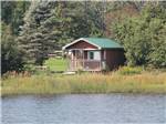 A cabin with porch on the banks of a lake at PONDEROSA PINES CAMPGROUND - thumbnail