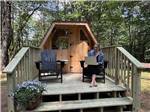 A woman sitting on the porch of her rental cabin - thumbnail
