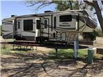 View larger image of A fifth wheel trailer with a picnic bench at OVERNITE RV PARK image #2
