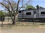View larger image of A motorhome next to the fenced in tree at OVERNITE RV PARK image #8