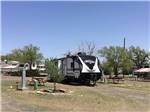 View larger image of A travel trailer in a gravel pull thru site with a picnic table at OVERNITE RV PARK image #10