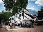 Family sitting at a picnic table next to a 5th wheel at GARDEN OF THE GODS RV RESORT - thumbnail