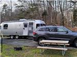 A picnic table next to a car and travel trailer at PRINCE WILLIAM FOREST RV CAMPGROUND - thumbnail
