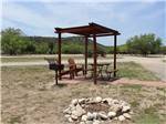 Two chairs and table under a gazebo next to a fire pit at NORTH LLANO RIVER RV PARK - thumbnail
