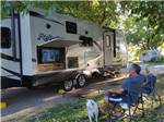 A couple sitting outside their RV watching TV at THE PARKWAY RV RESORT & CAMPGROUND - thumbnail