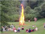 View larger image of People surrounding a large bonfire at CAMP TOODIK FAMILY CAMPGROUND CABINS  CANOE LIVERY image #3