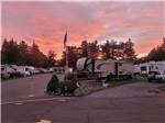 RVs parked in sites against a beautiful sunset at Port Orford RV Village - thumbnail