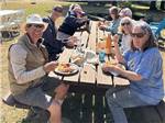 Eight people enjoying a picnic on a sunny day at Port Orford RV Village - thumbnail