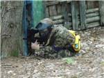View larger image of A person hiding behind a tree playing paintball at MEADOWBROOK CAMPING AREA image #8