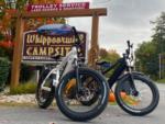 Electric bikes parked near the park sign at WHIPPOORWILL MOTEL & CAMPSITES - thumbnail