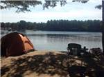 View larger image of Waterfront tenting site with a chair at WASSAMKI SPRINGS CAMPGROUND image #6