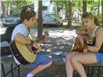 Two people hanging out playing acoustic guitars at ATLANTIC SHORE PINES CAMPGROUND - thumbnail